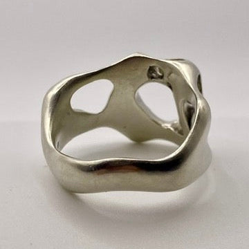 Silver ring with an organic modern design on a light gray background