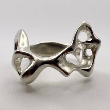 Silver ring with a unique, organic design on a light gray background