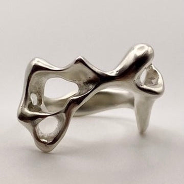 Silver ring with a unique, organic design on a light gray background