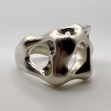 Silver ring with a unique, organic design on a light gray background
