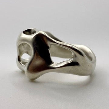 Silver ring with a unique, organic design on a light gray background