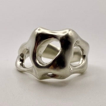 Silver ring with a unique organic design on a light gray background