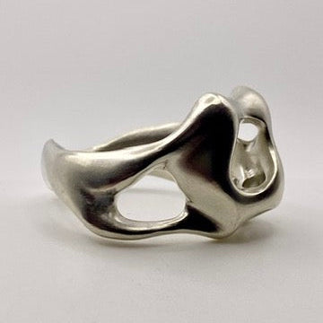 Silver ring with a unique organic design on a light gray background